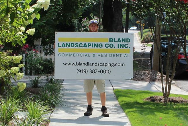 A Bland team member holding up a sign with company contact information