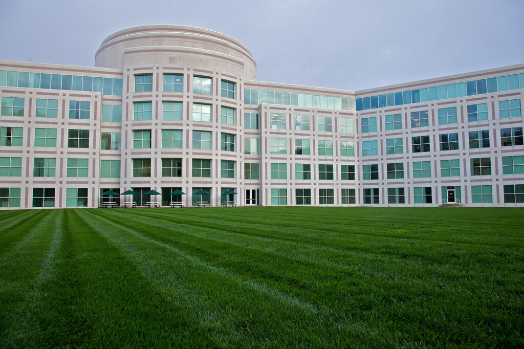 A view of a large white office building with freshly mowed turfgrass