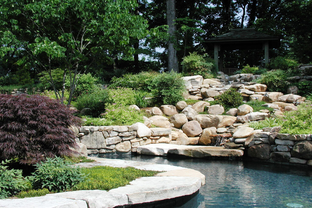 Landscape design with a rocky hillside and manmade waterway around a circular landscape feature