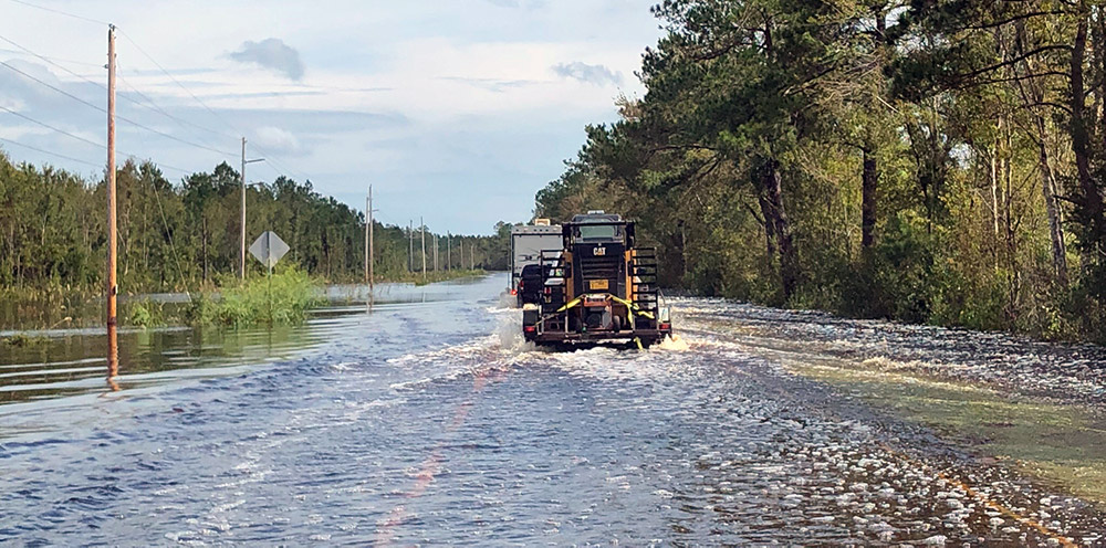 Machinery traveling along a road flooded by storm water
