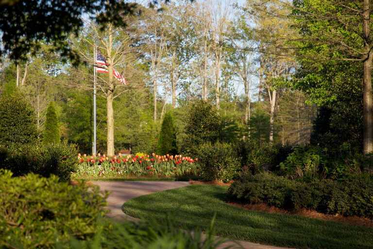 Hardscape design with flowers, trees, and shrubs featuring the American Flag in the middle