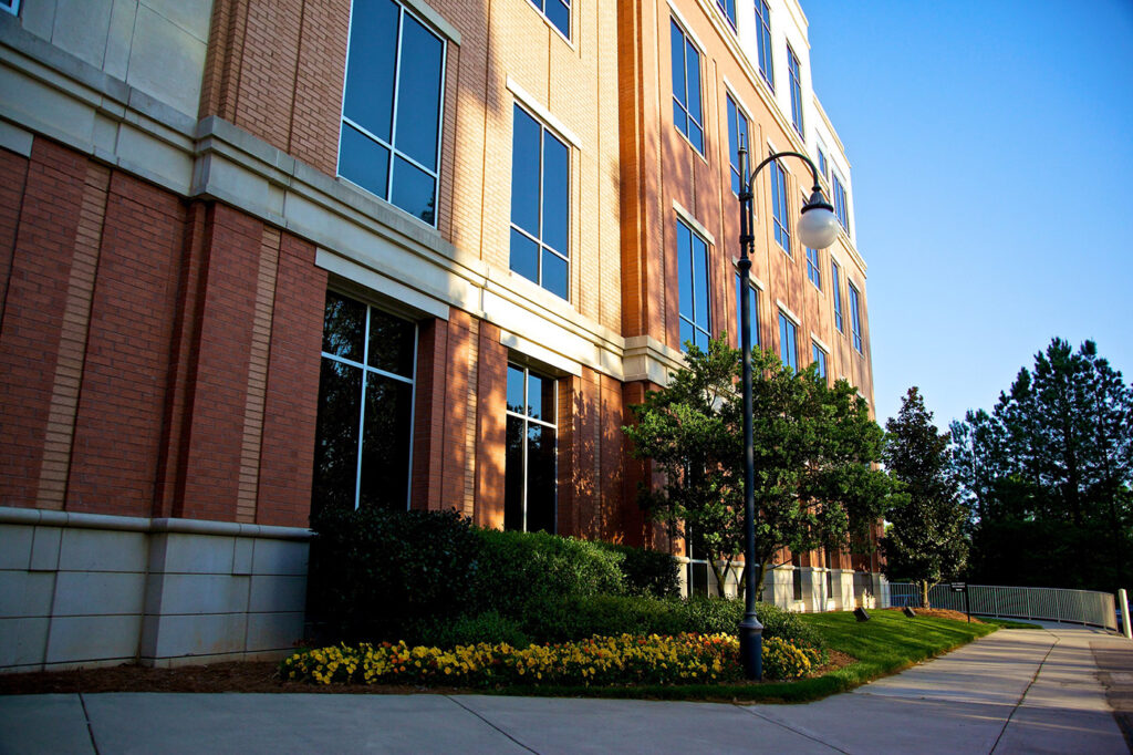Building with manicured trees, grass, and flowers at Palisades