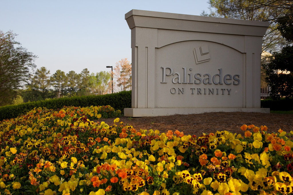 A closeup of signage and yellow flowers Palisades on Trinity